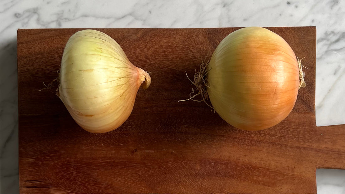 Two onions on a cutting board ready to be cut without crying